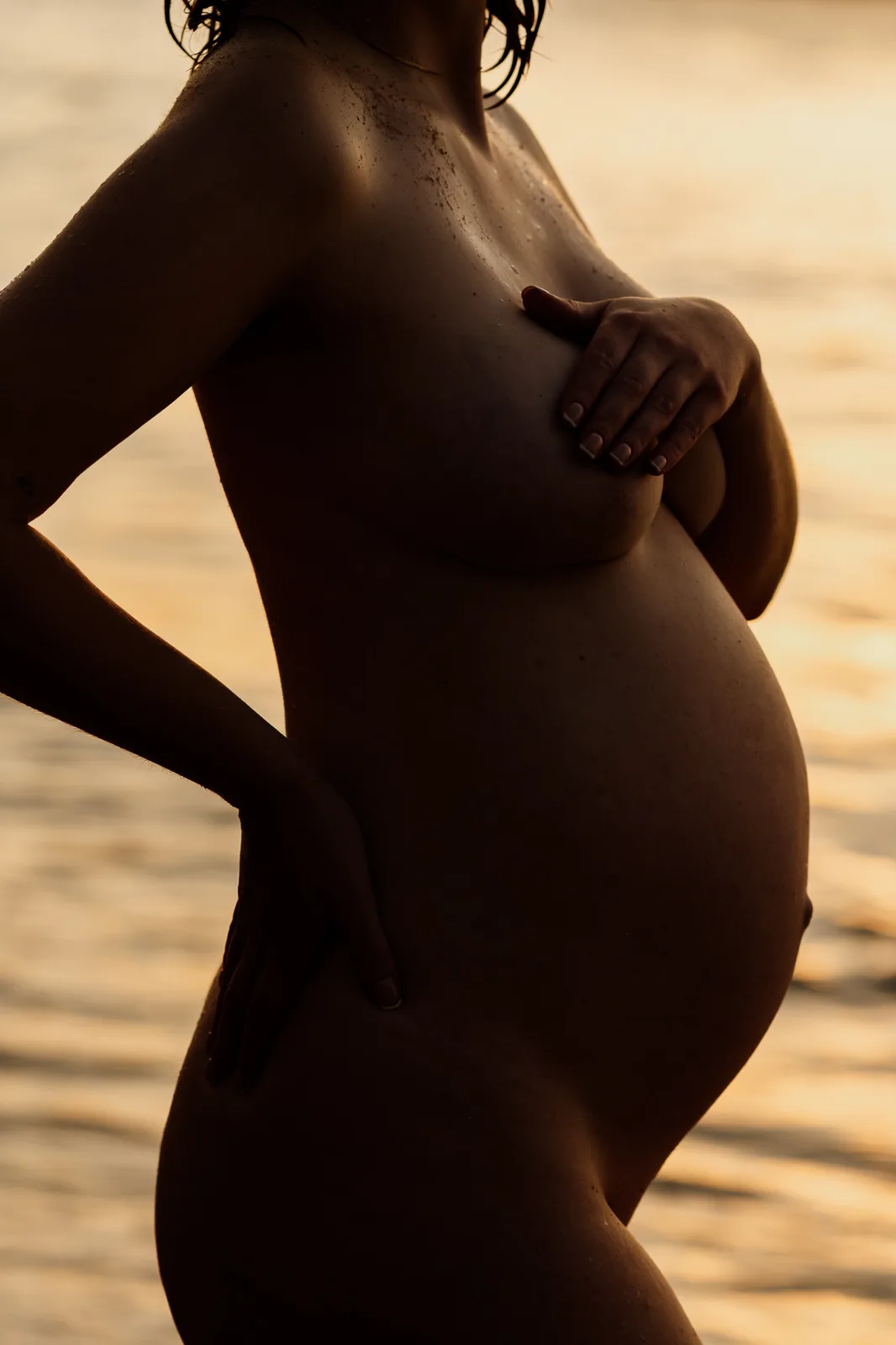 Close-up of a pregnant belly in golden light during a Sydney implied-nude maternity session
