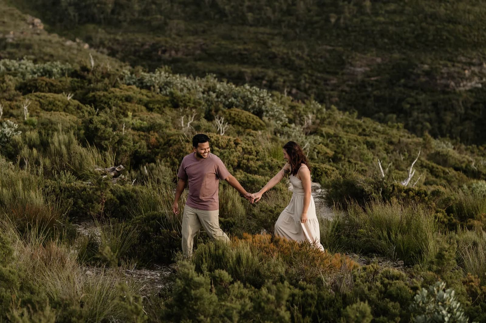 Couple walking a grassy hillside in the Blue Mountains at golden hour