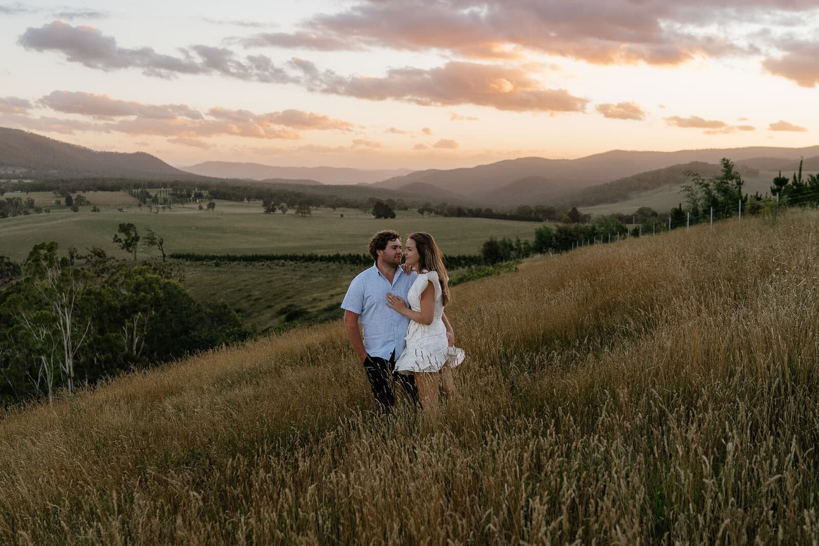 Couple walking a grassy hill at sunset, photographed by Nerissa J Photography in Sydney