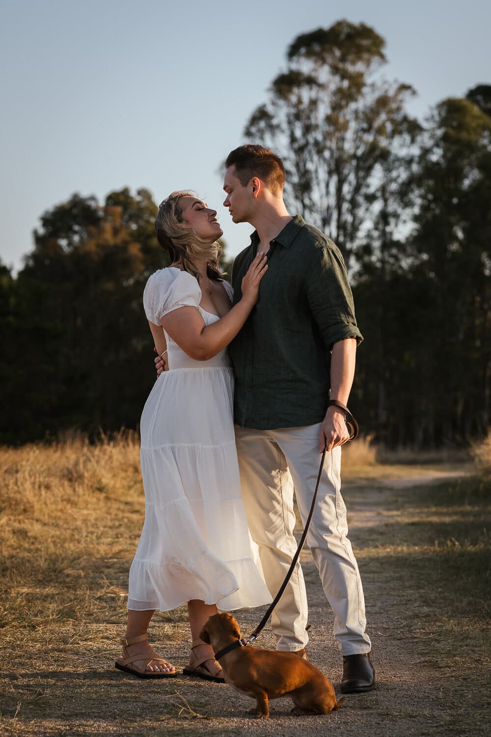 Couple with their dog in an open field at golden hour