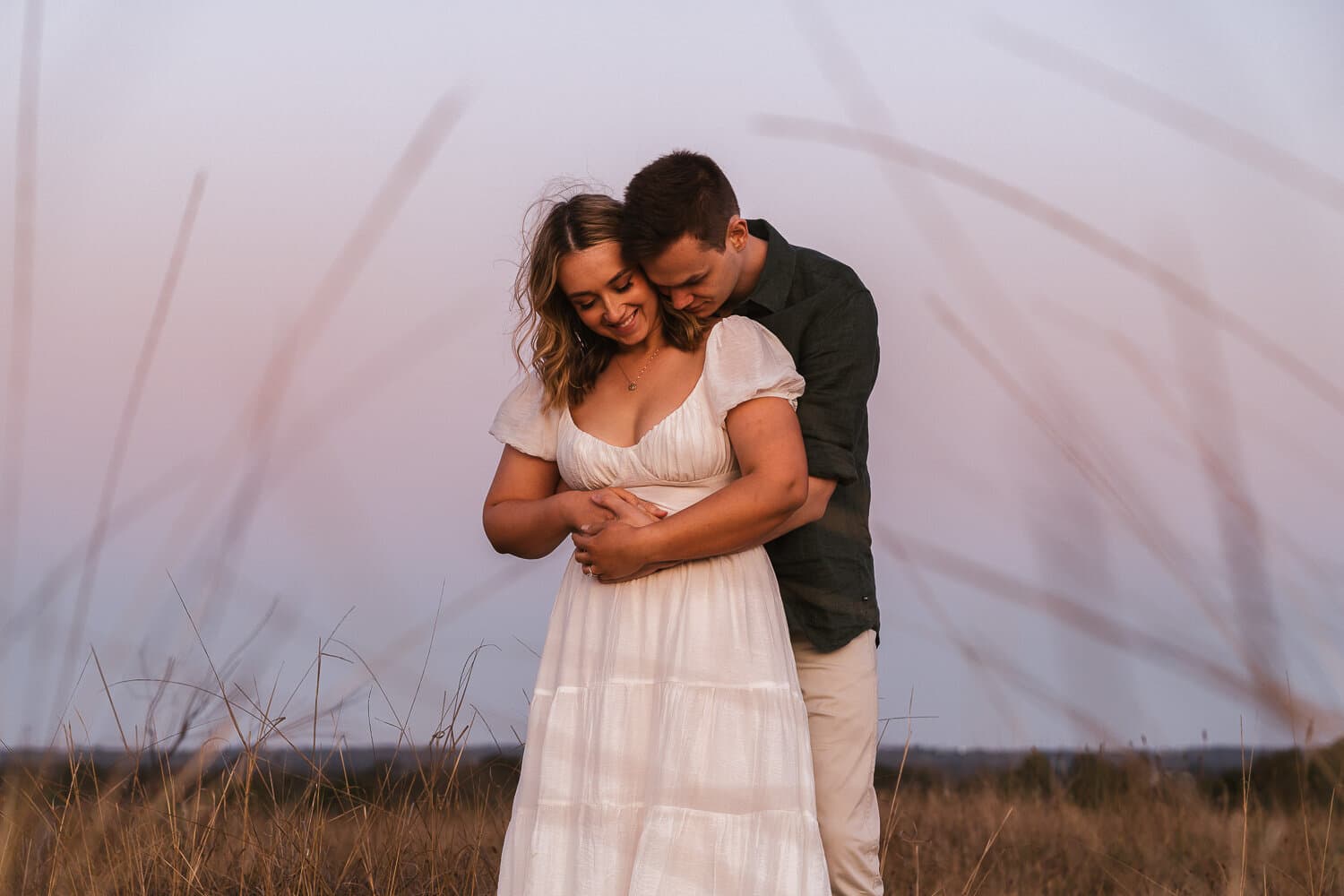 Couple close together in long grass at dusk