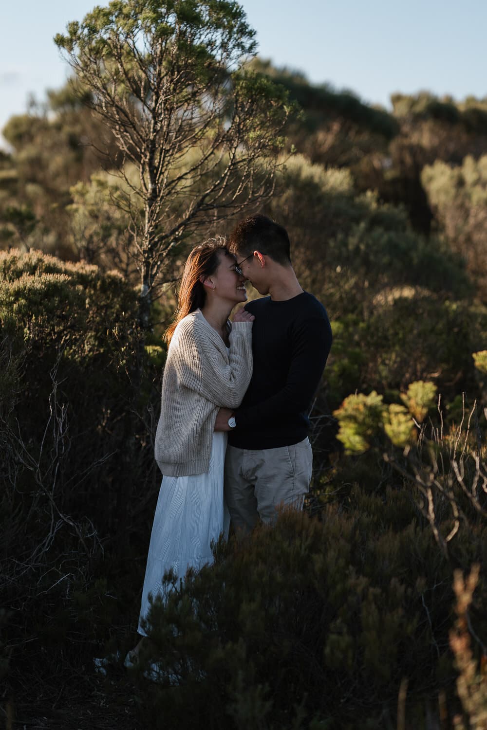 Couple standing close together among the trees at golden hour near Sydney