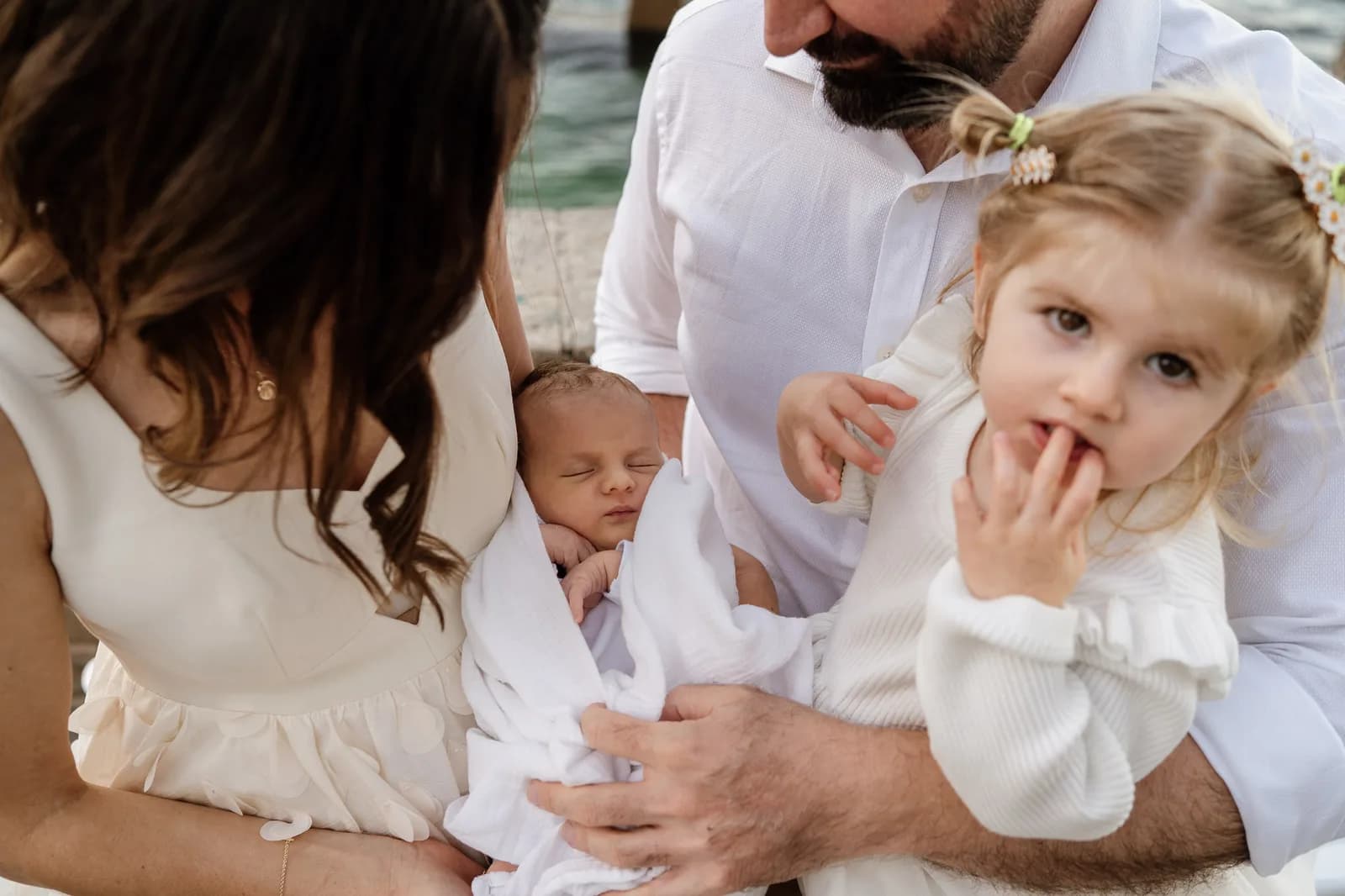 Family in white on the sand with their baby during a Sydney beach photoshoot