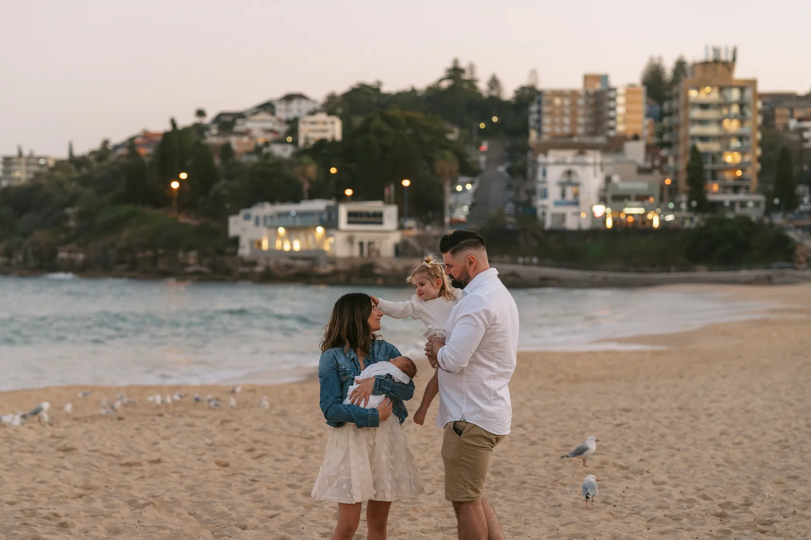 Family on the beach at golden hour with the headland behind them in Sydney