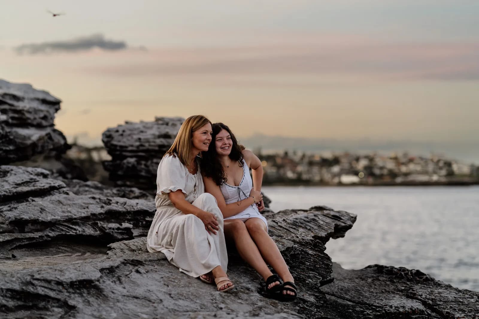 Family on coastal rocks at sunset with the Sydney coastline behind them