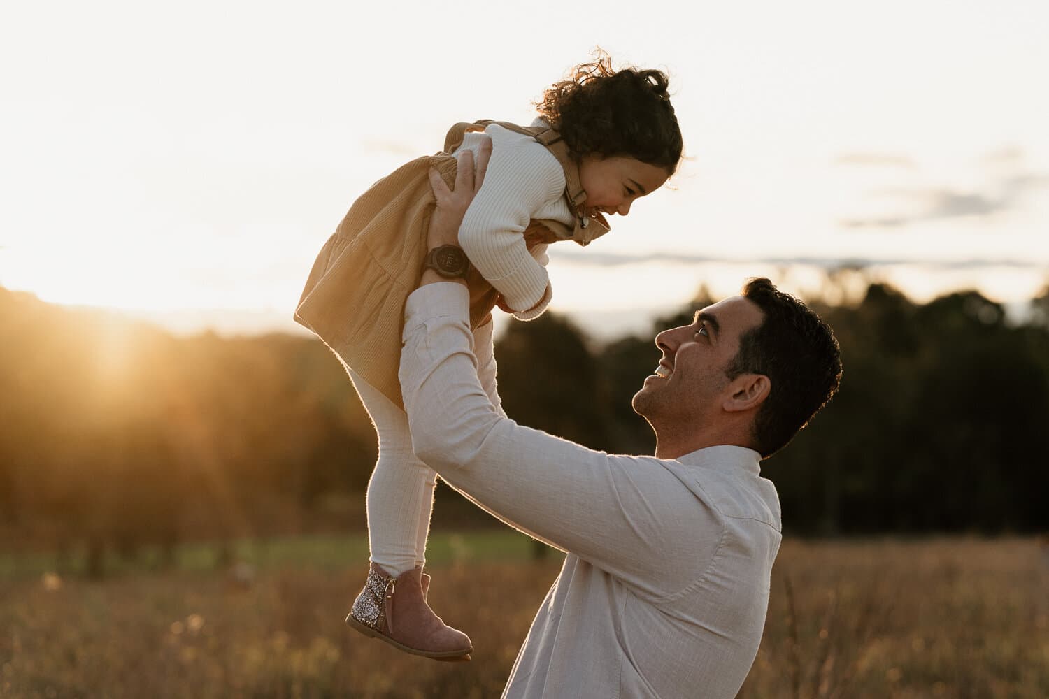 Father lifting his daughter into the air in golden afternoon light during a Sydney family shoot