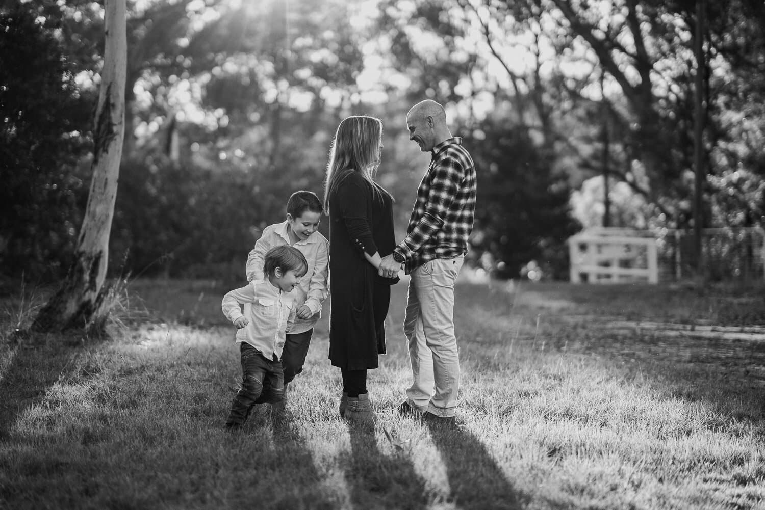 Black and white frame of a family walking a bush track together