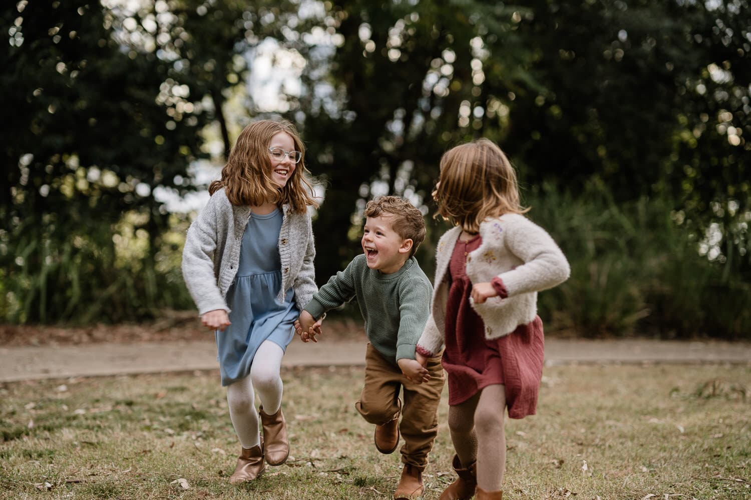 Children running together through the bush during a candid family session
