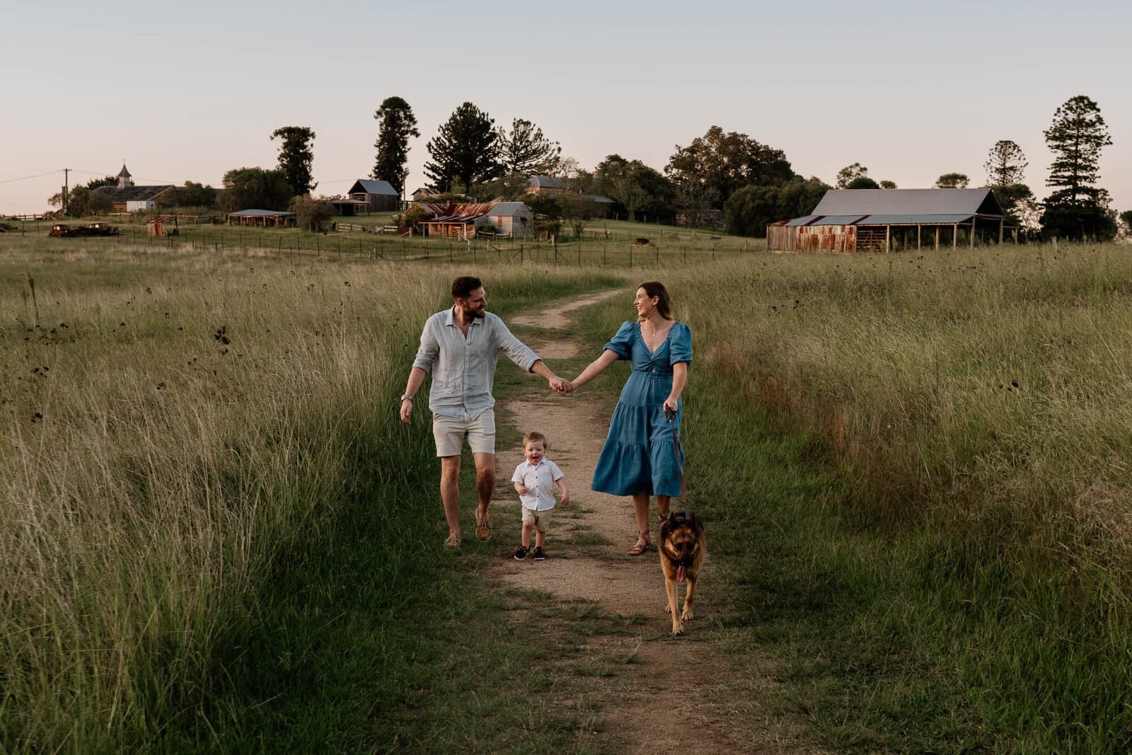 Family walking hand in hand down a country track at sunset during a candid lifestyle photography session in Sydney