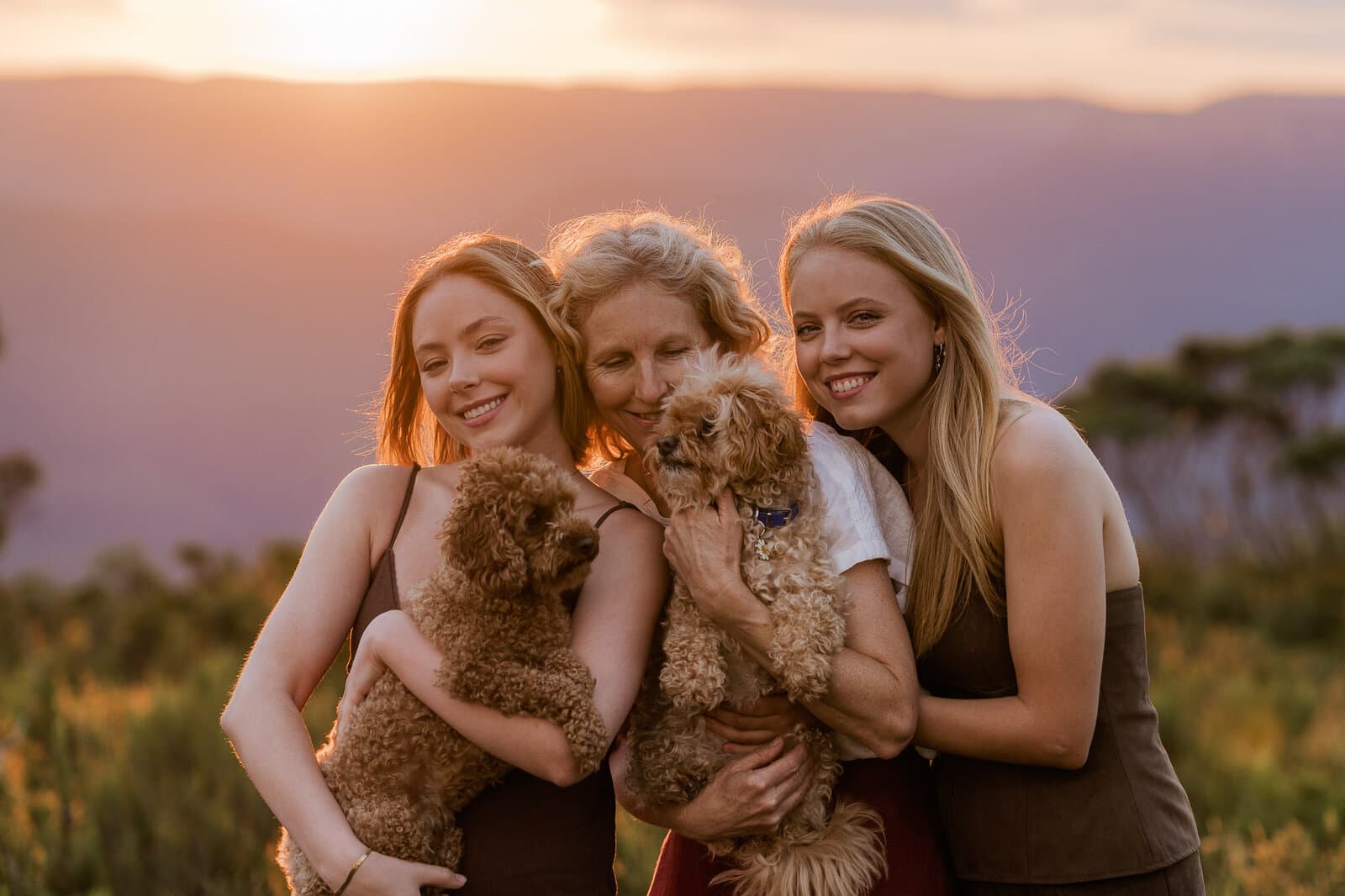 Sisters and their puppies backlit by the setting sun during a family session near Sydney
