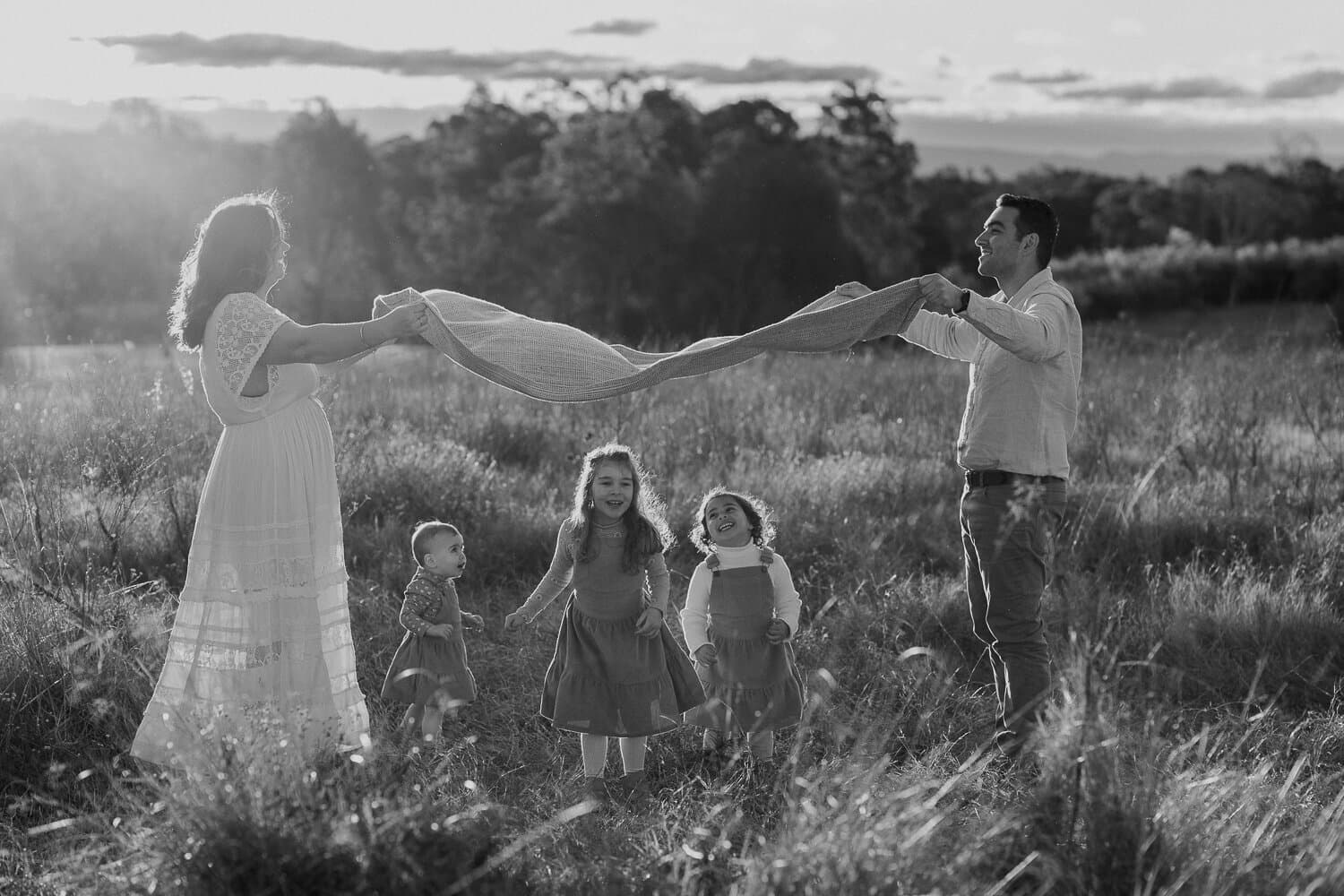 Black and white frame of parents swinging their child between them