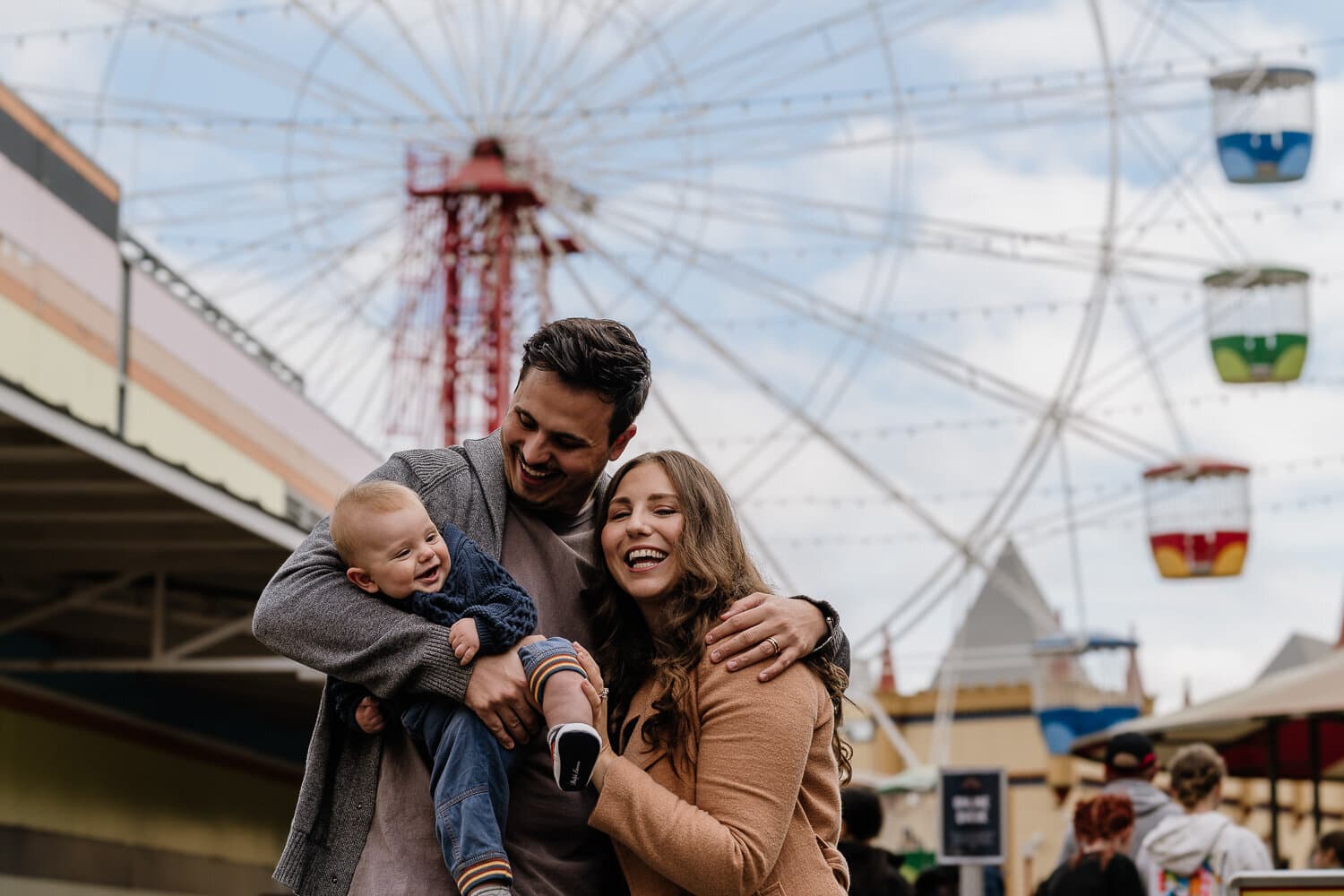 Family at a fairground with the ferris wheel behind them