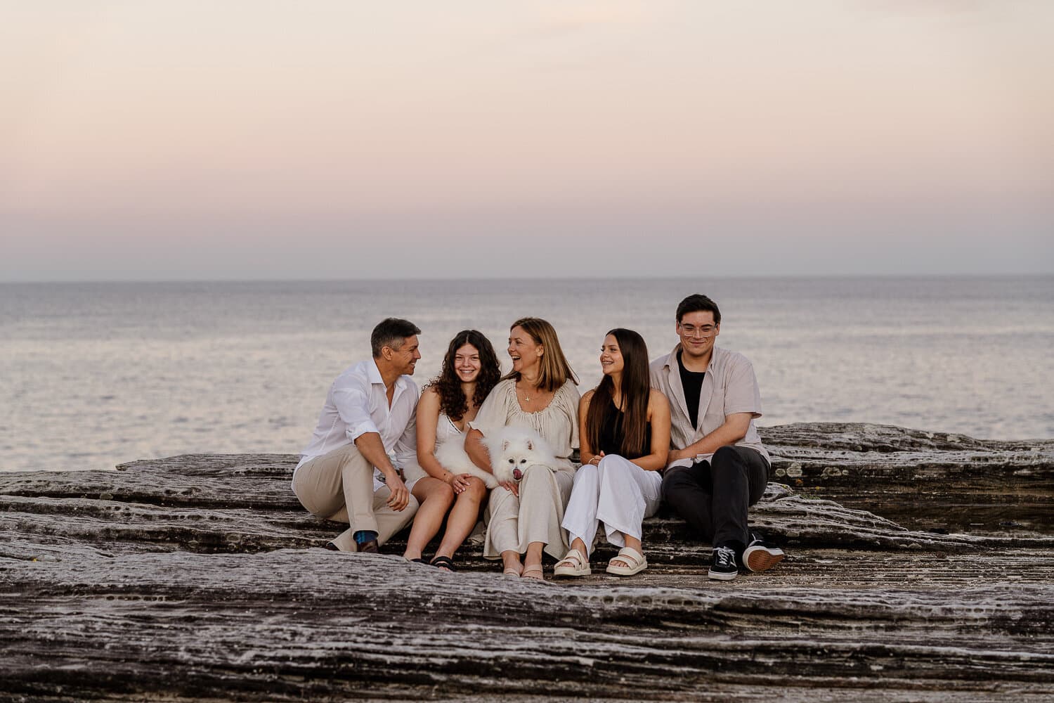 Extended family seated together on the headland overlooking the water