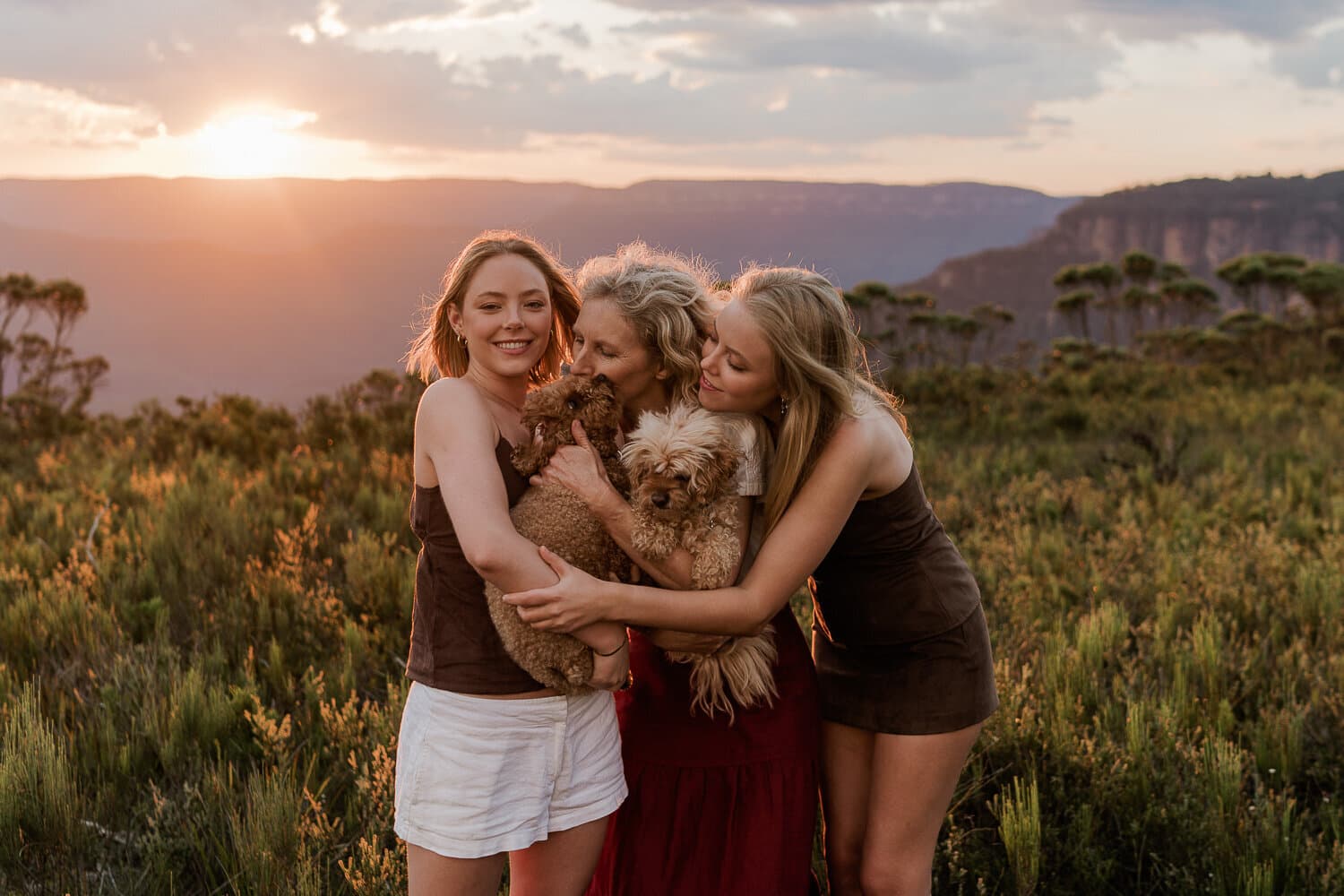 Mother and daughters embracing at sunset with the valley behind them