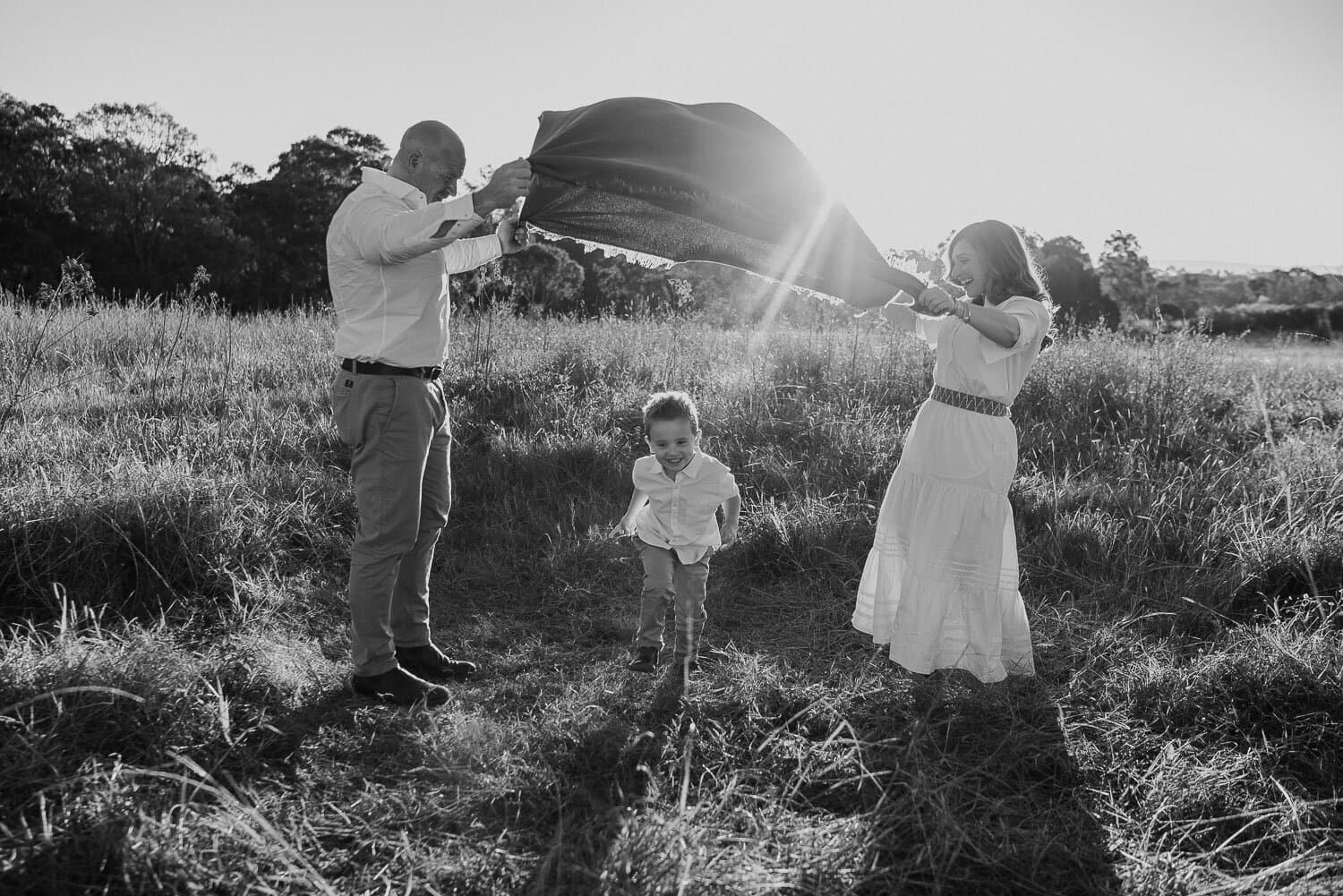 Black and white frame of parents and their daughter in an open field
