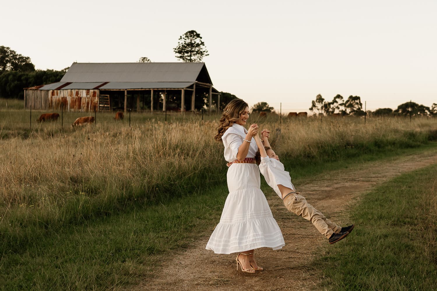 Woman walking a path towards a homestead at golden hour