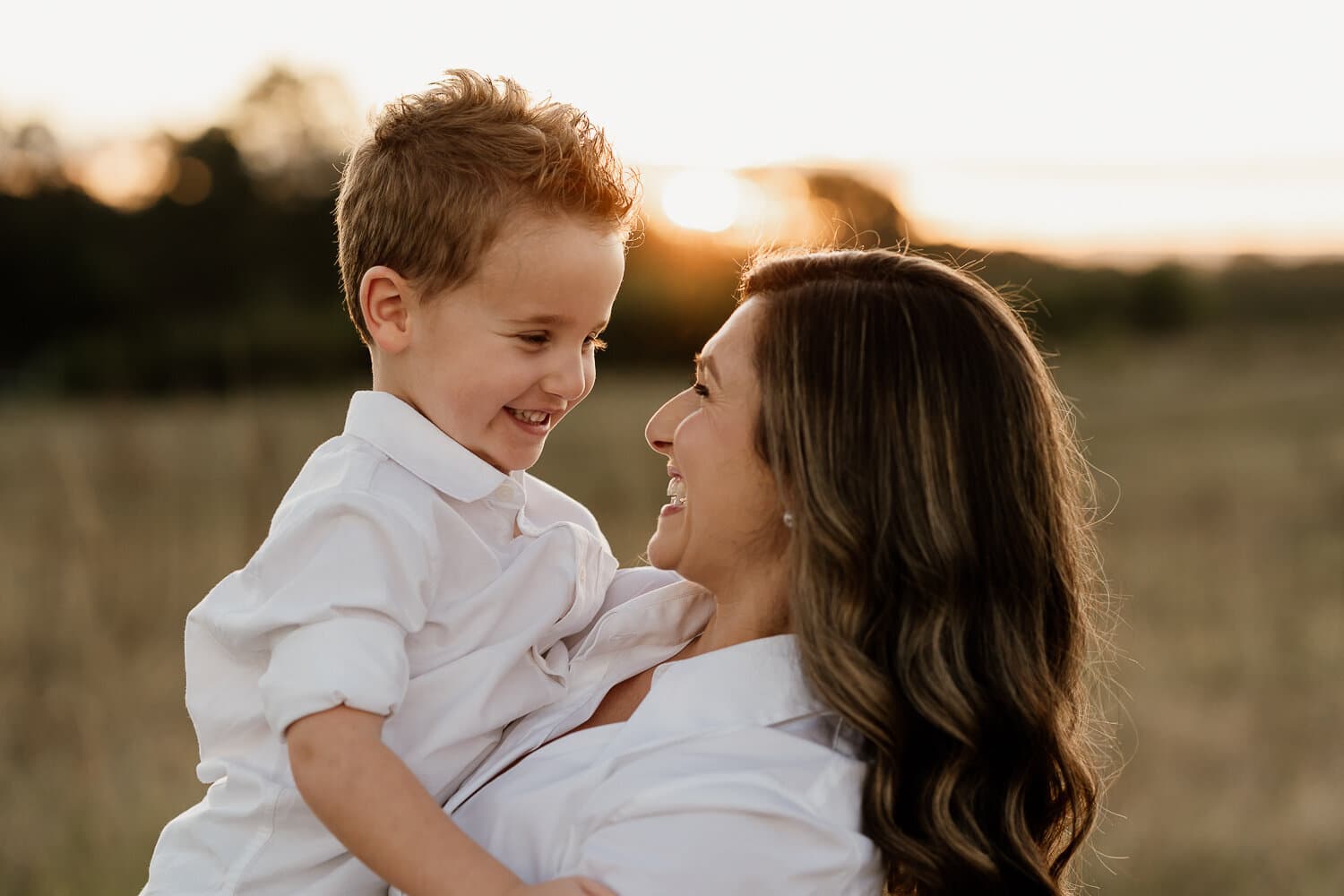 Mother and son laughing together in a golden field