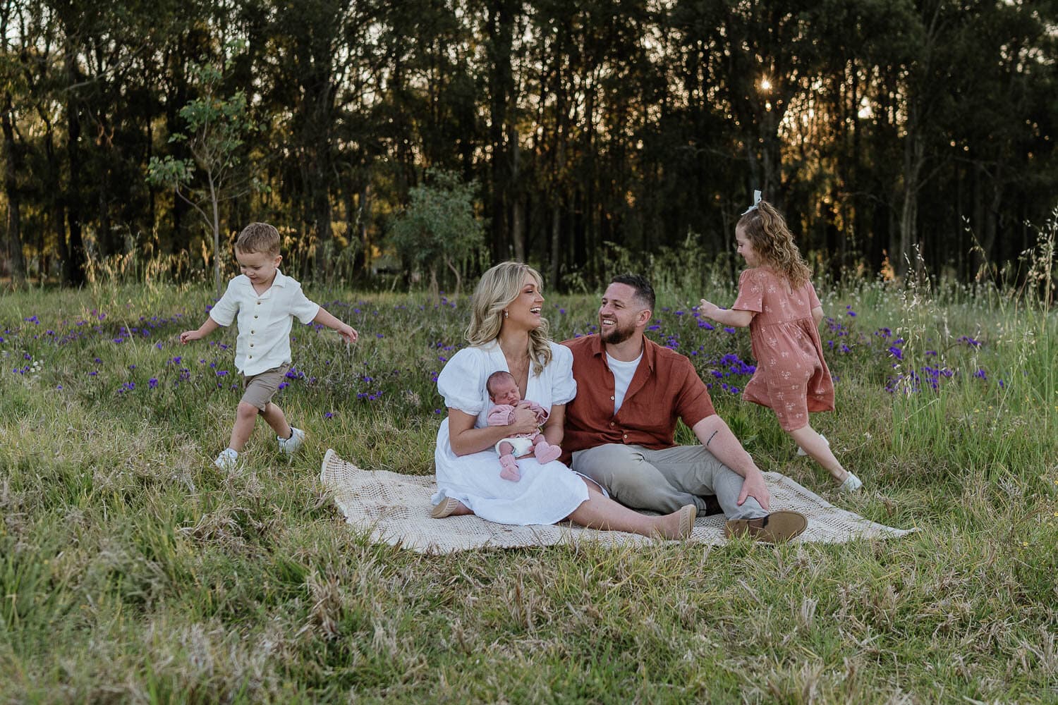 Family relaxing on a picnic rug among the trees