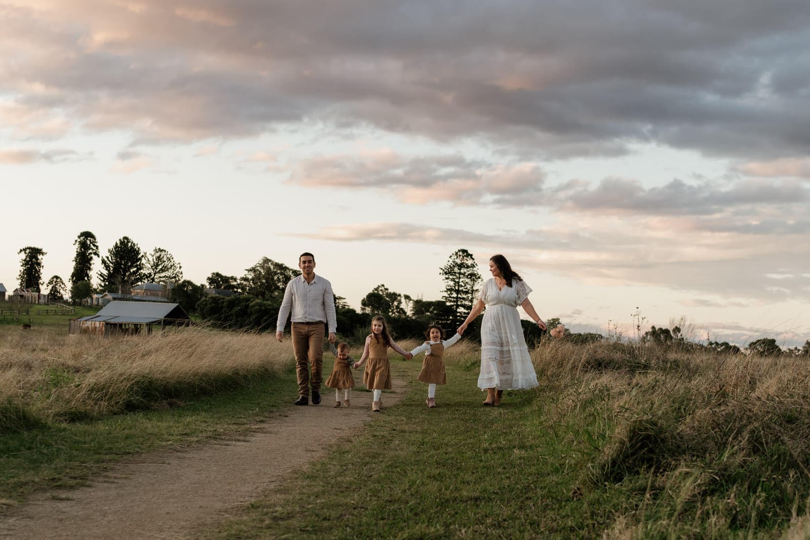 A family of 6 walking a country path hand in hand at dusk during a Sydney family session