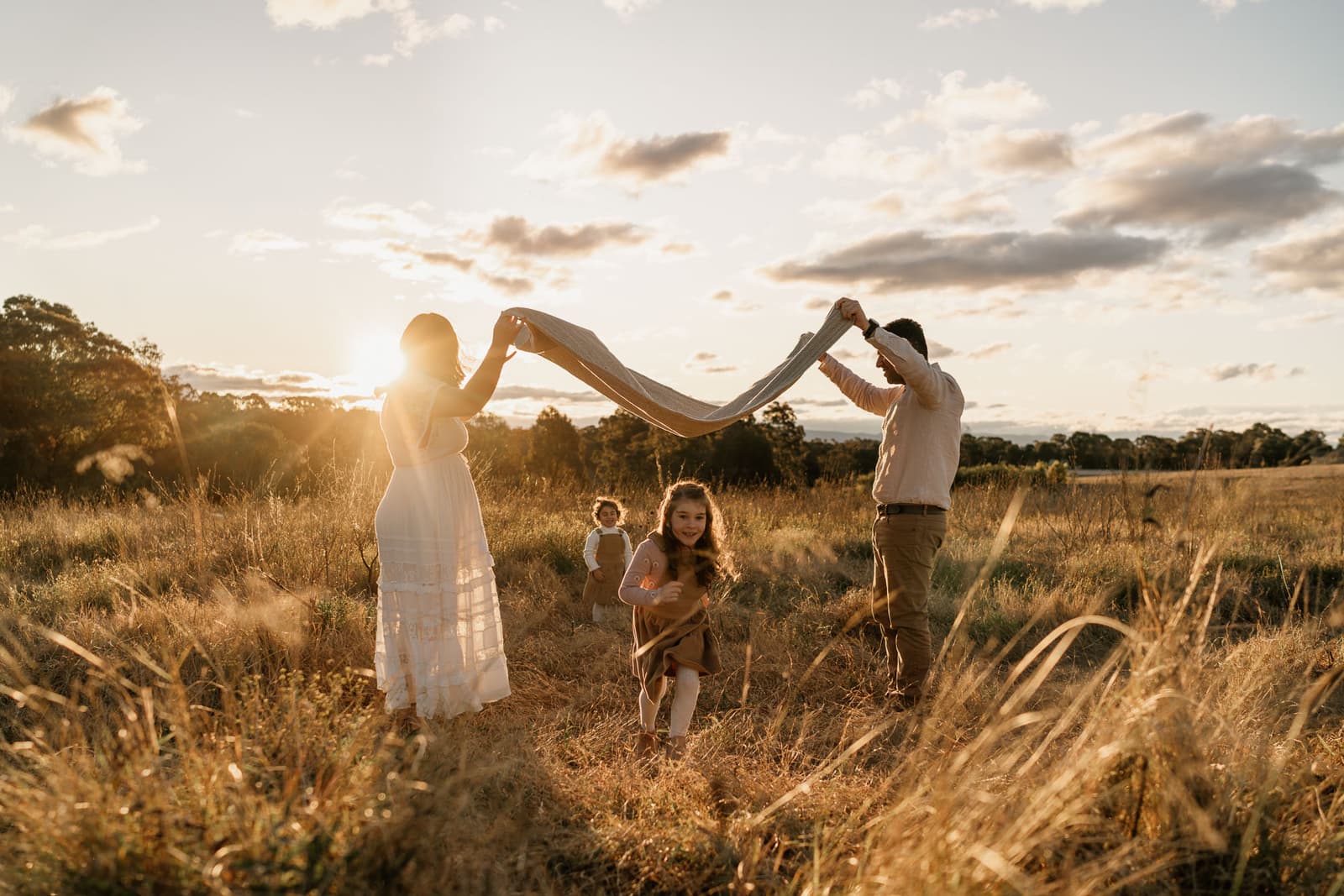 Family walking together through a golden field at sunset during a Sydney family photography session