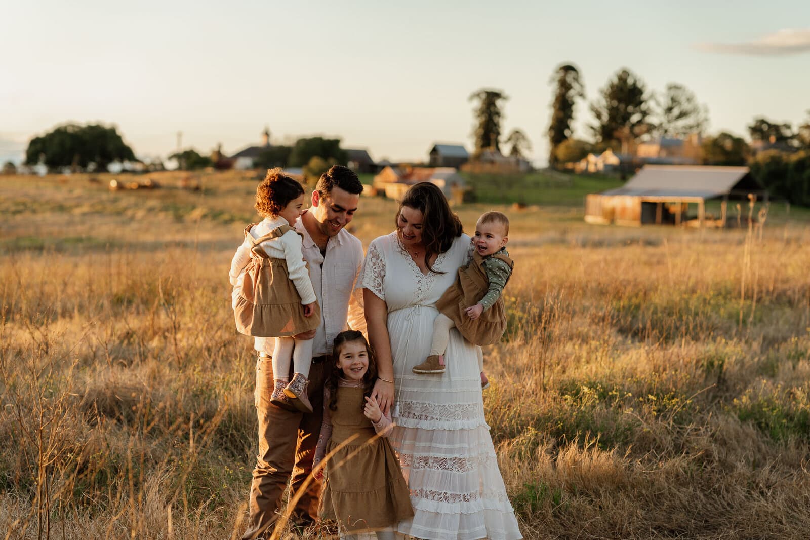 Family photographed together in an open field at golden hour near Sydney
