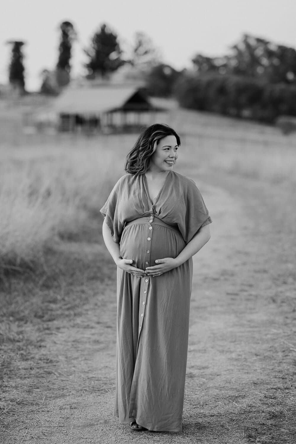 Black and white maternity portrait of a mother-to-be on a country path
