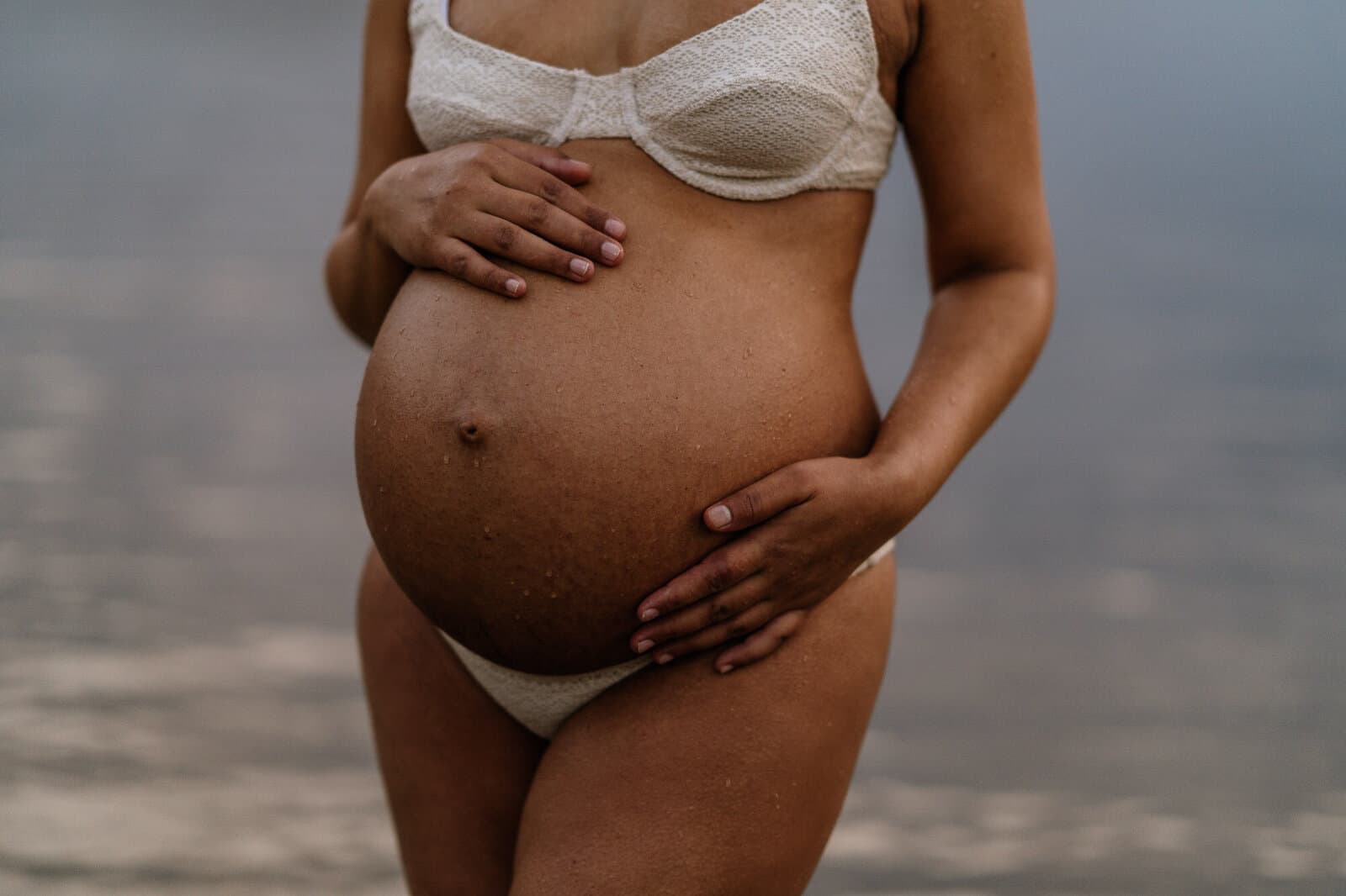 Close-up detail of a baby bump cradled by the mother's hands