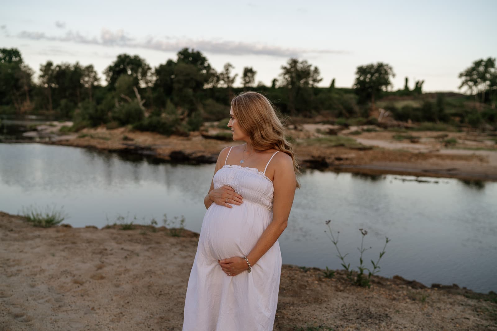 Expecting mother on the riverbank at golden hour