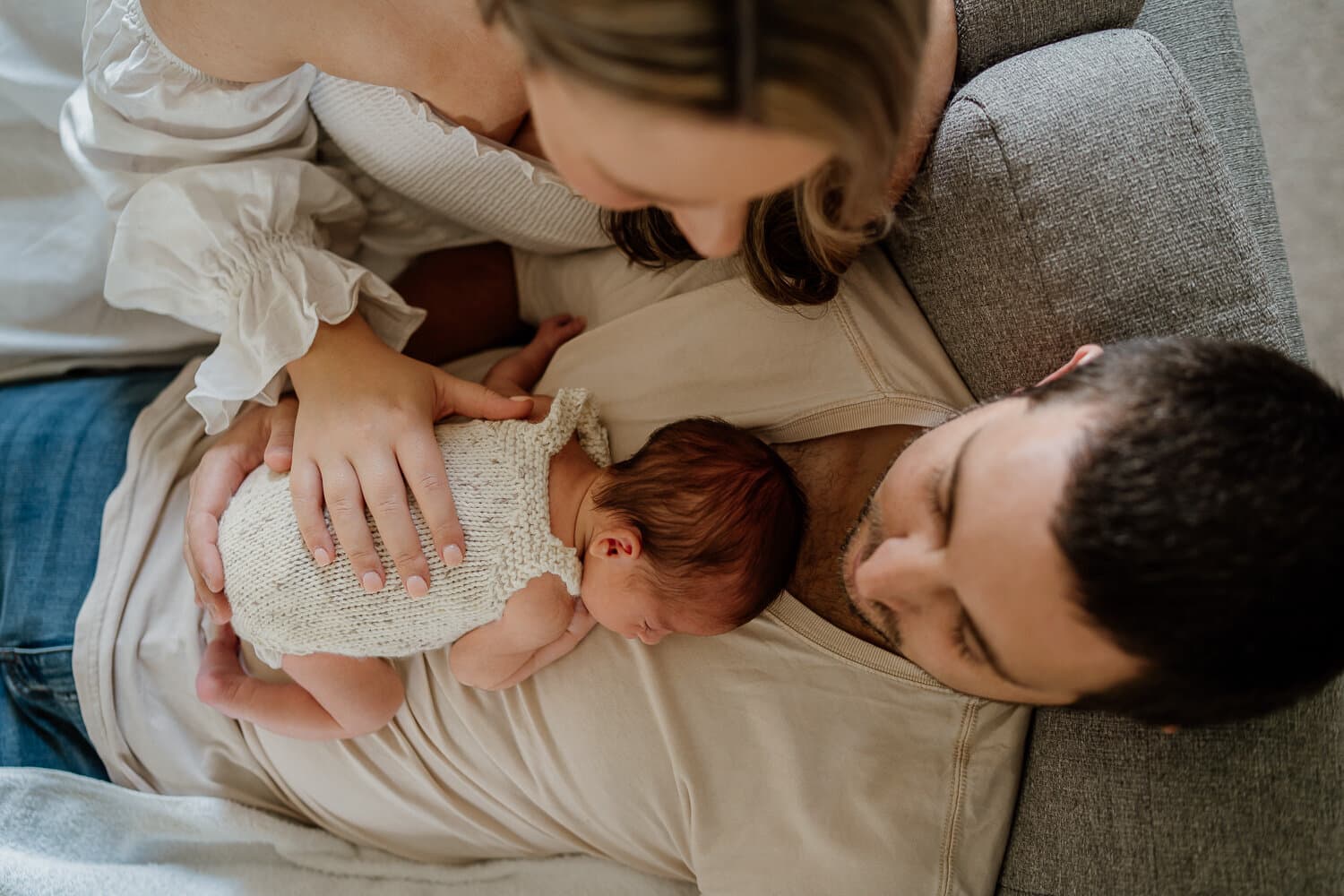 Mother kissing her newborn while dad looks on at home