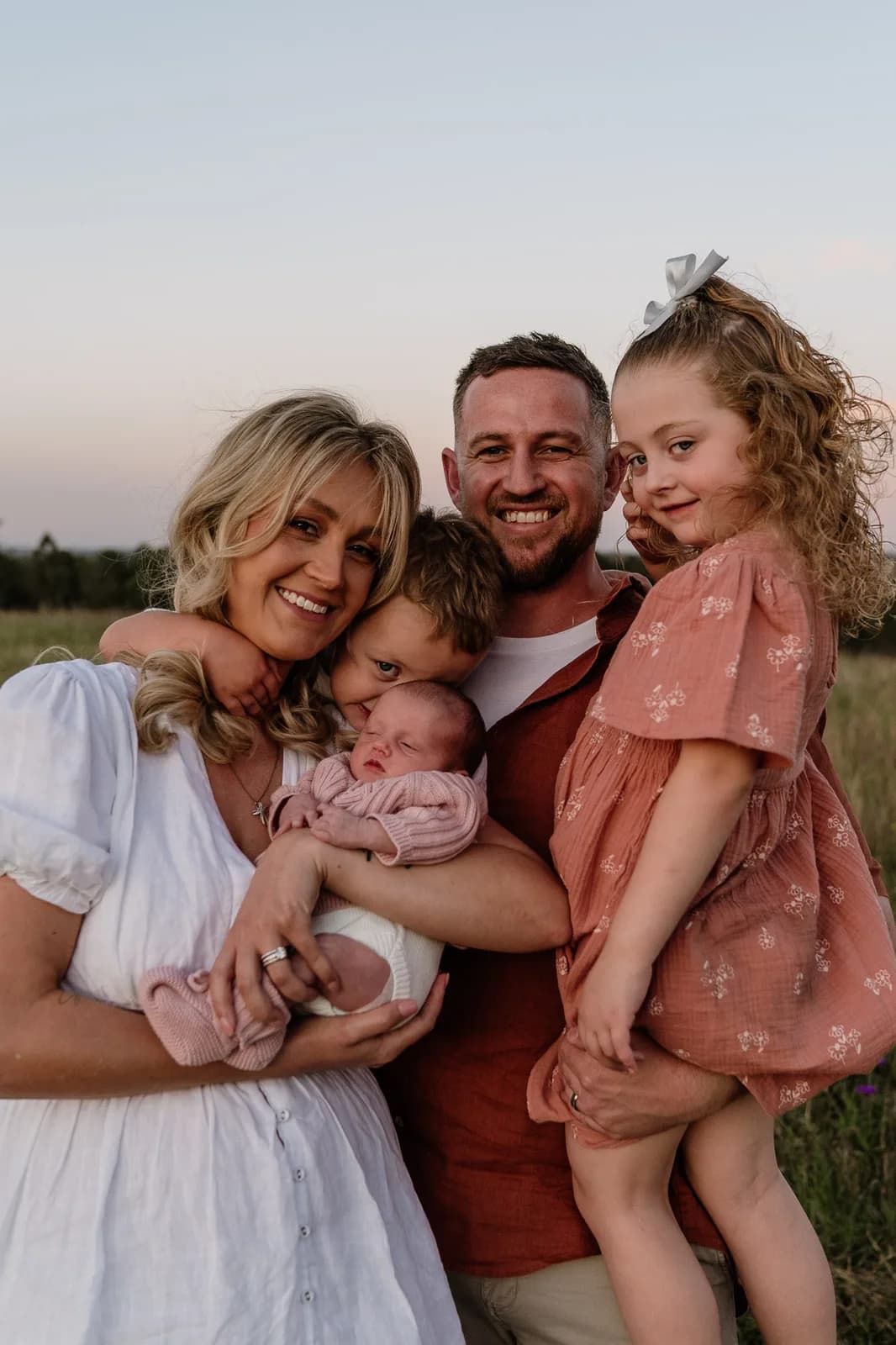 Family of 5 close together with their newborn at golden hour