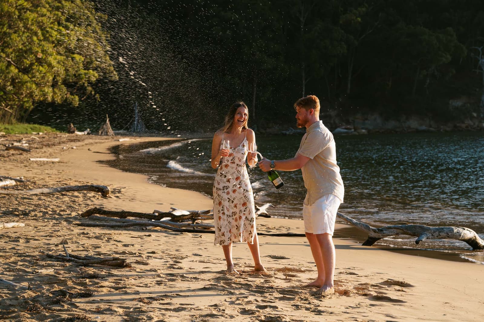 Newly engaged couple laughing together on the shoreline moments after the proposal
