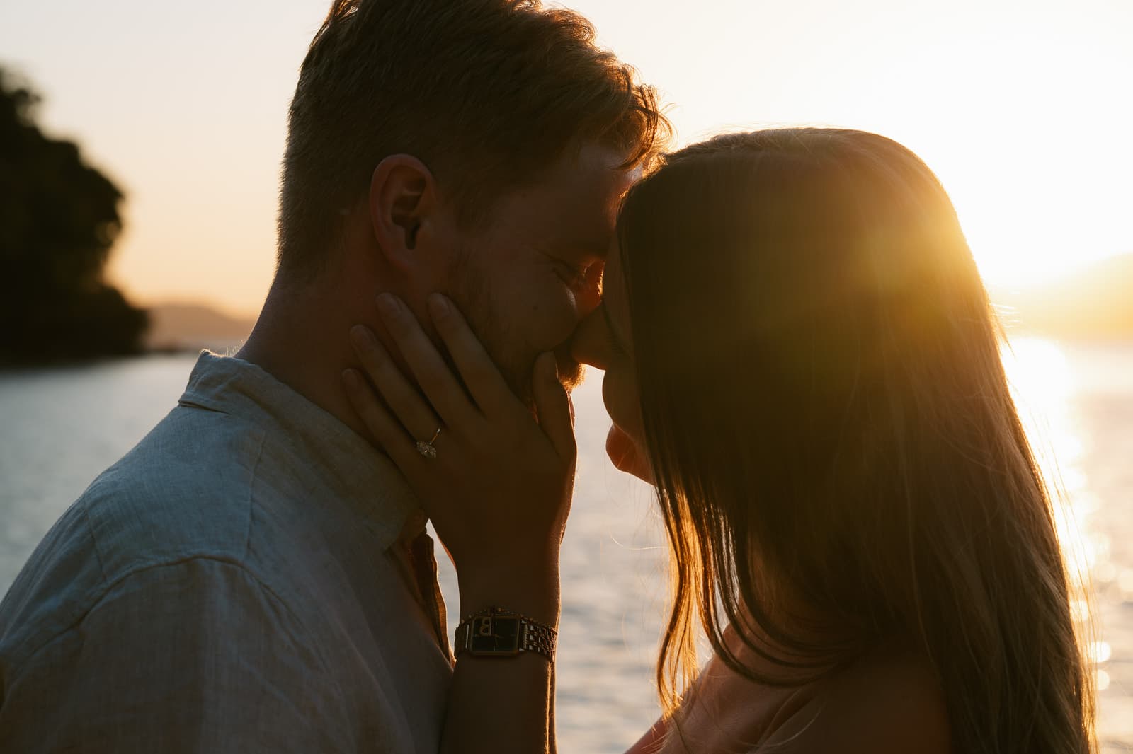 Just-engaged couple foreheads together, backlit by the setting sun