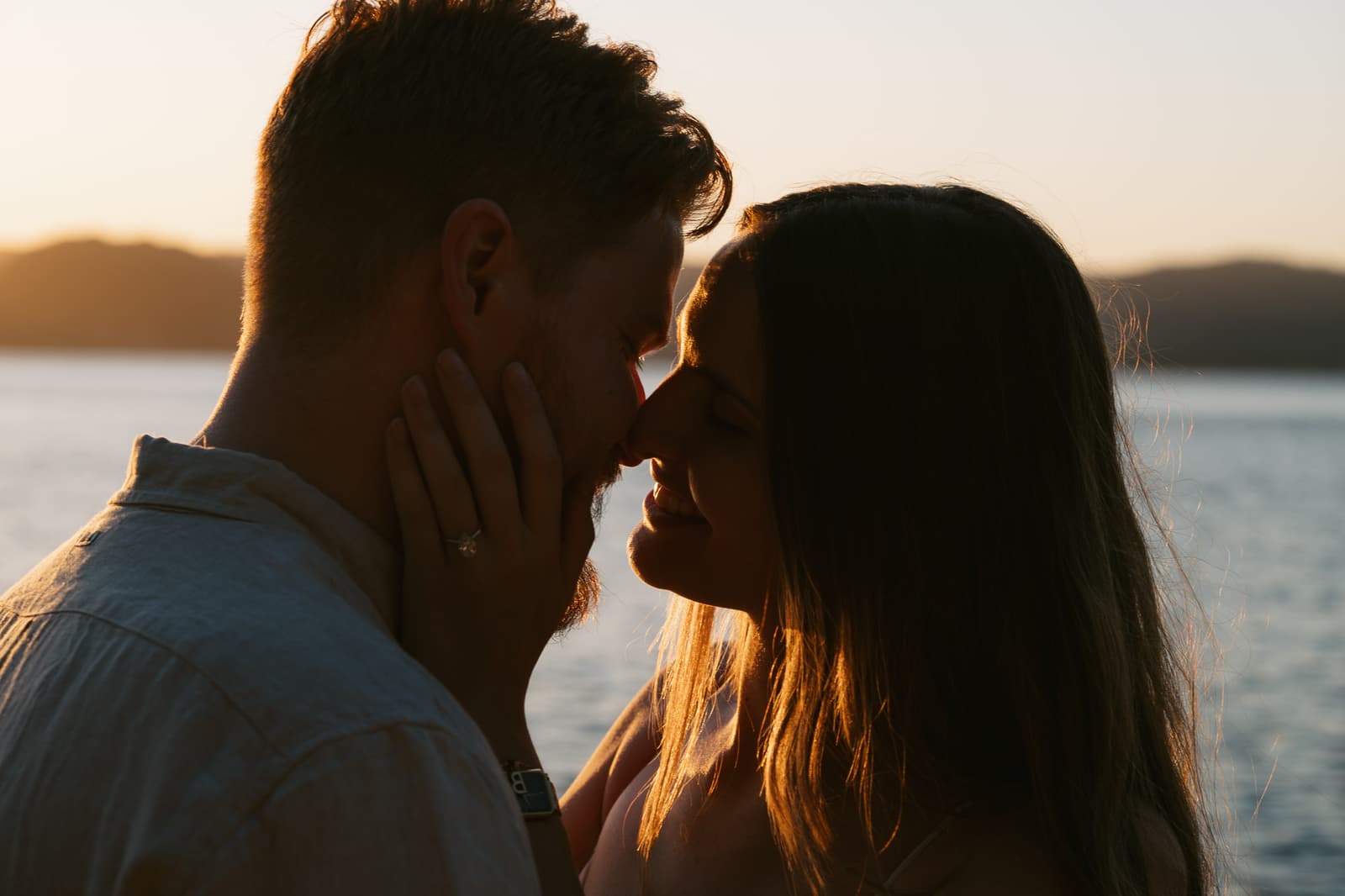 Couple kissing at sunset with the headland behind them