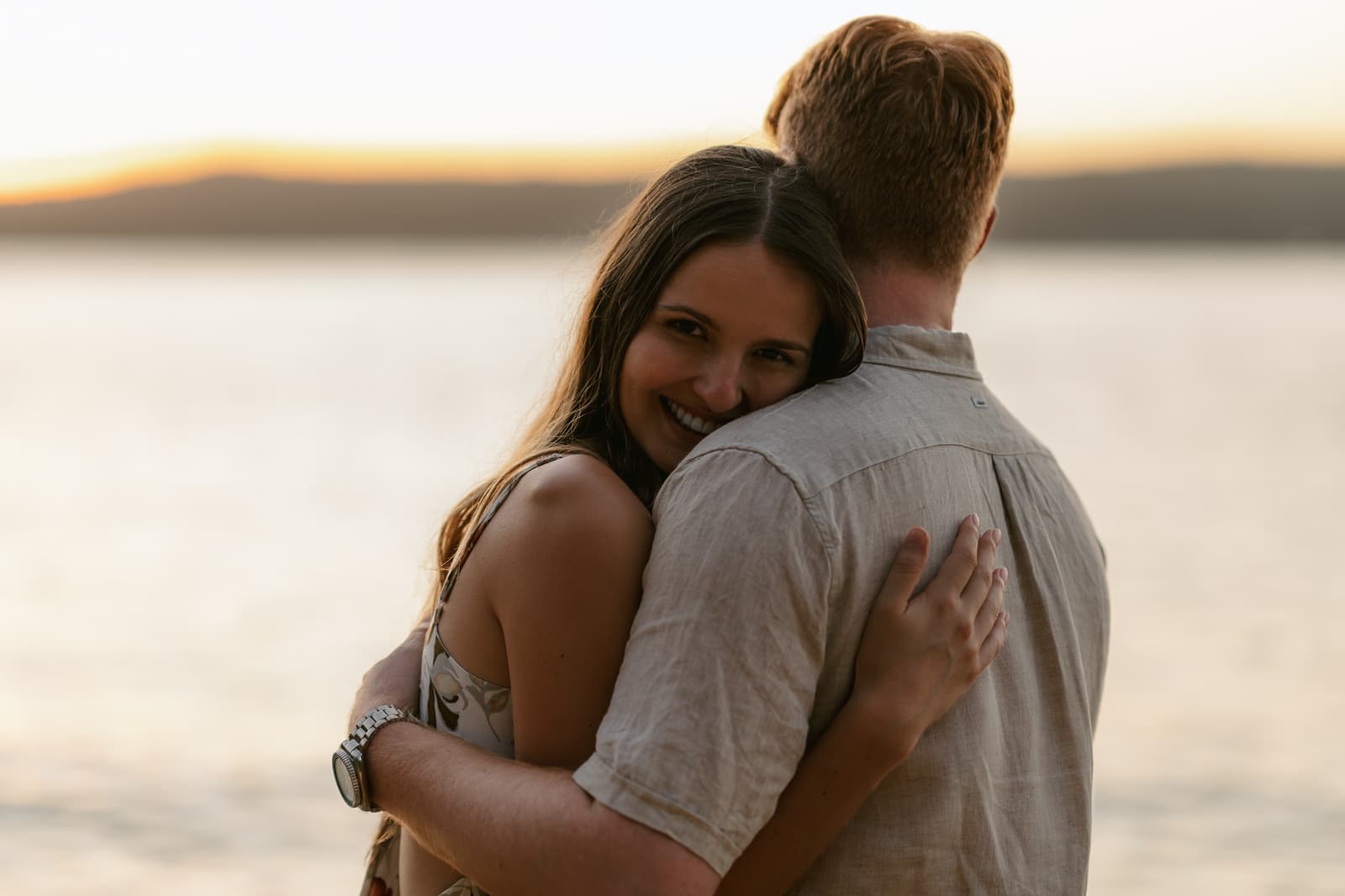 Couple holding each other by the water after saying yes