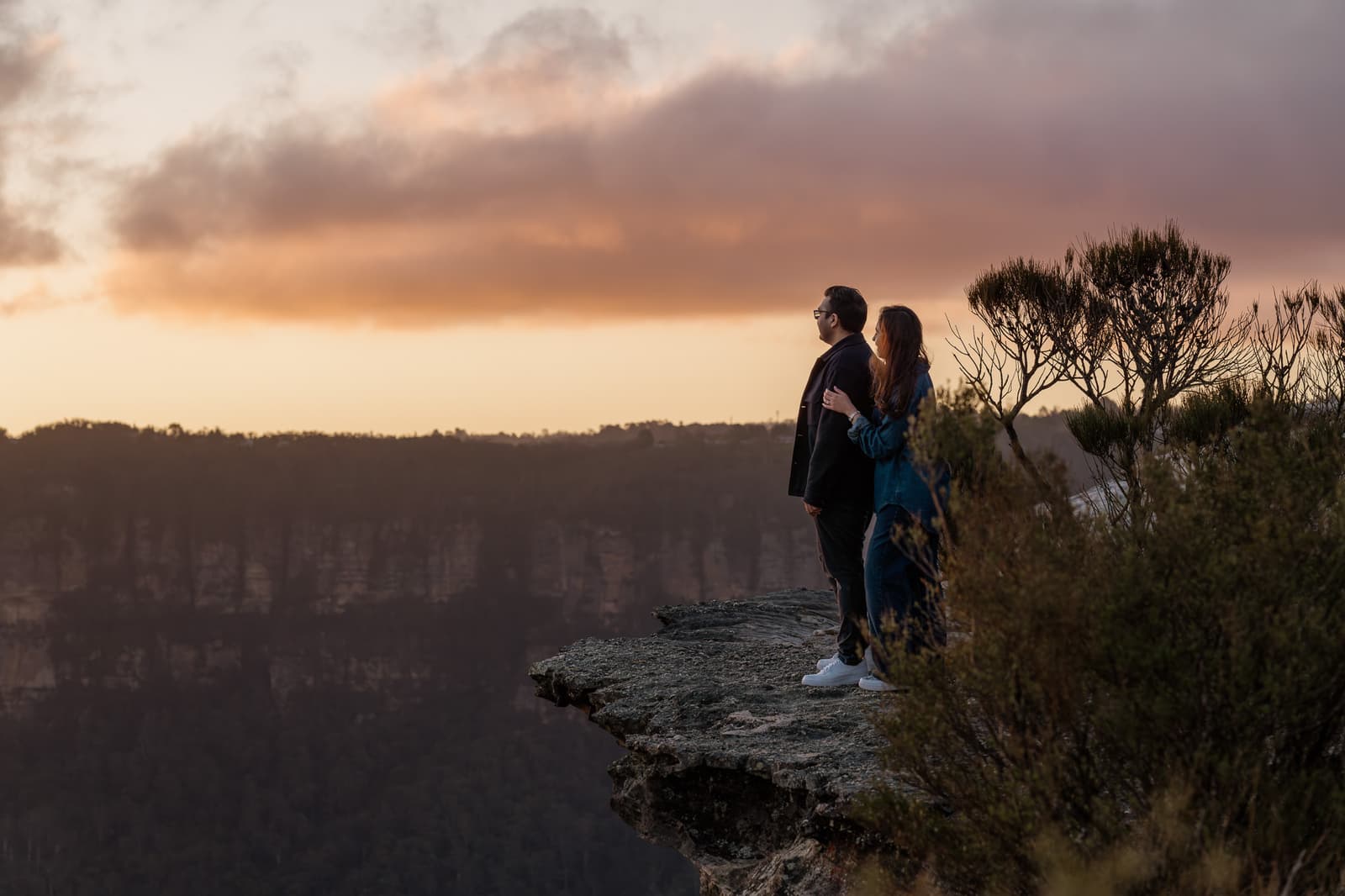 Couple standing at the edge of a Blue Mountains lookout at dusk