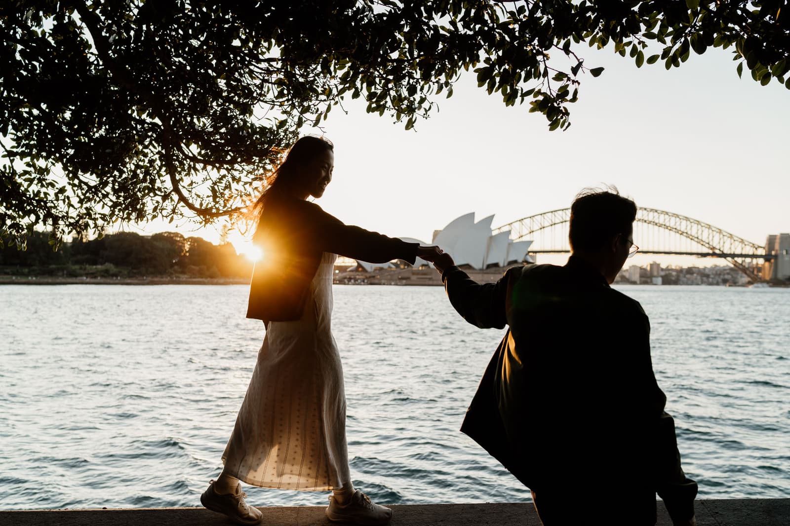 Newly engaged couple by the water with the Opera House behind them