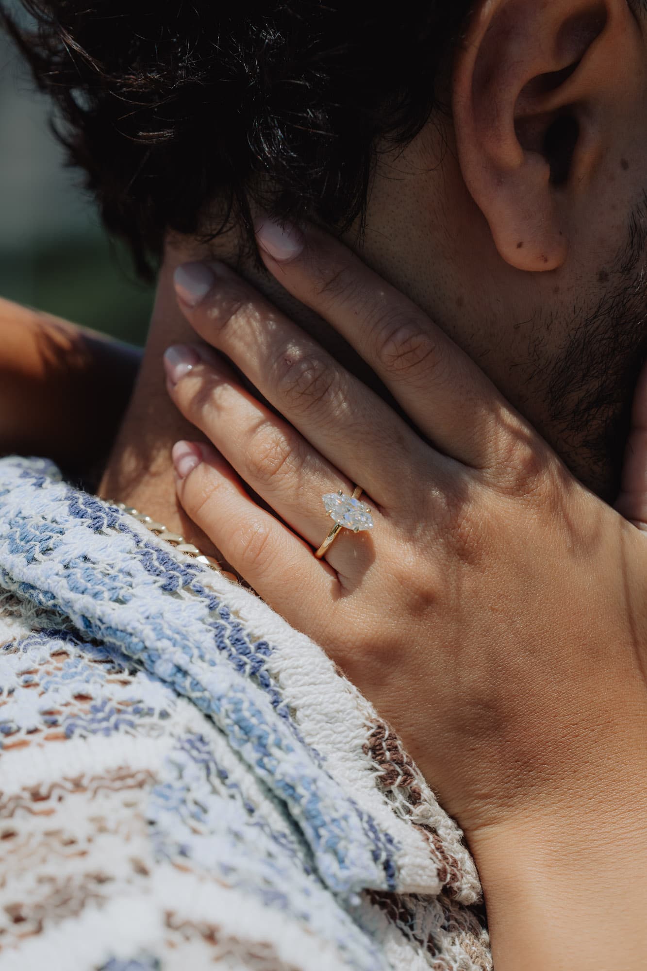 Her hand resting on his neck, the engagement ring catching the light