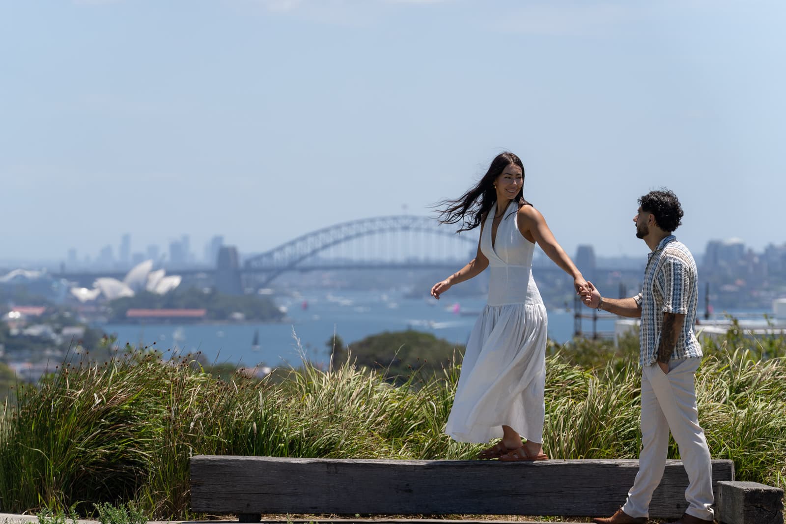 She walks towards him on the grass above the harbour, Opera House behind