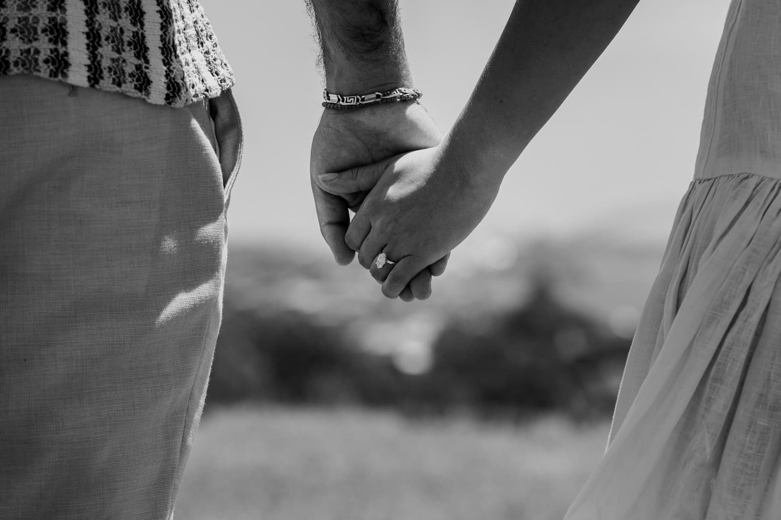 Black and white close-up of their hands held together, ring visible
