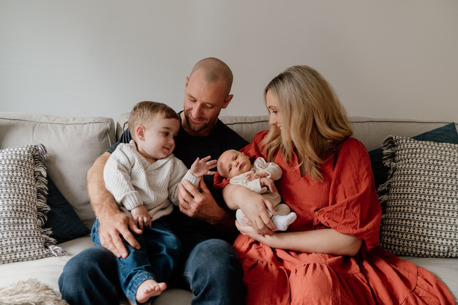 Parents and their toddler meeting the new baby together on the couch at home