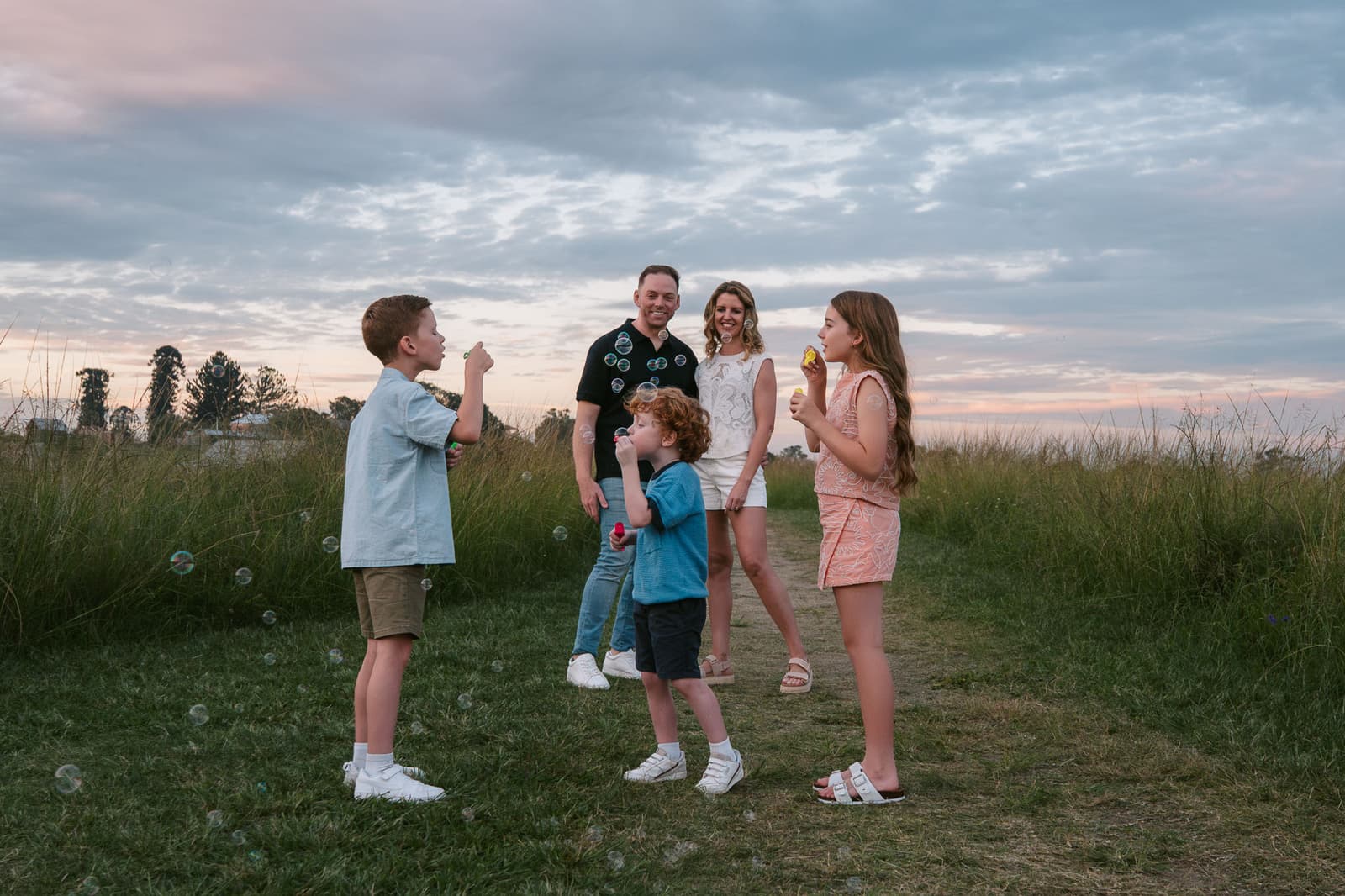 Family playing together in a Hills District field under a soft evening sky